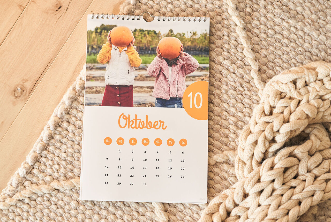 Twee kinderen met pompoenen op hun hoofd staan voor een kalender van oktober.
