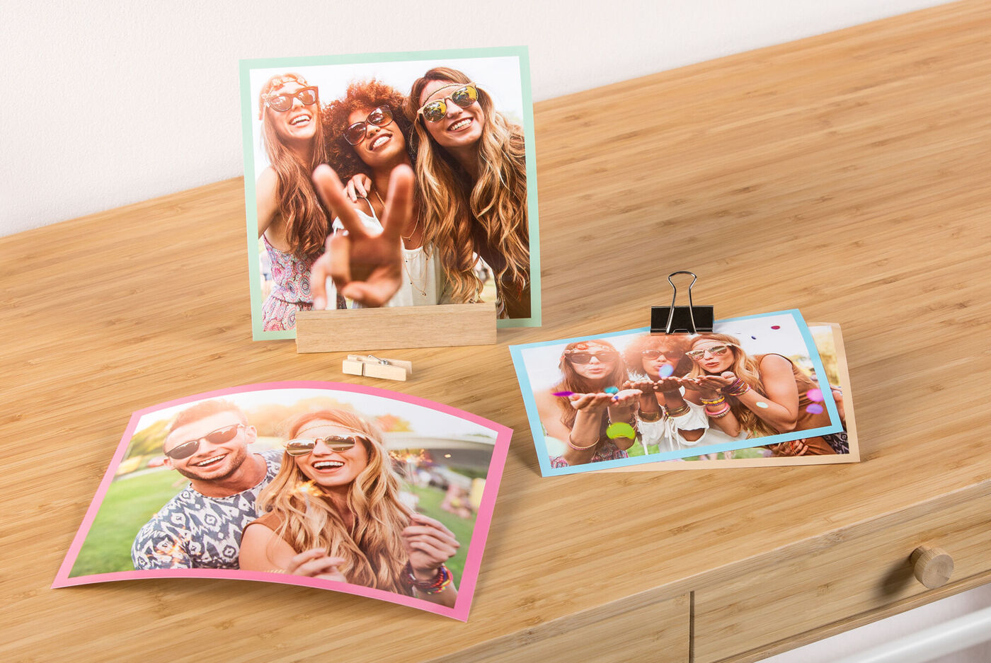 Vier kleurrijke prints liggend en staand op een houten oppervlak