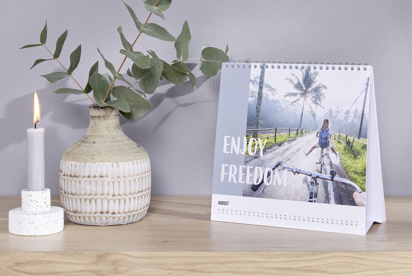Bureaukalender met fietser op weg tussen palmbomen en tekst enjoy freedom