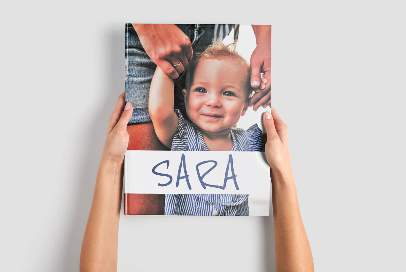 Iemand houdt een fotoboek met de titel 'SARA' vast.