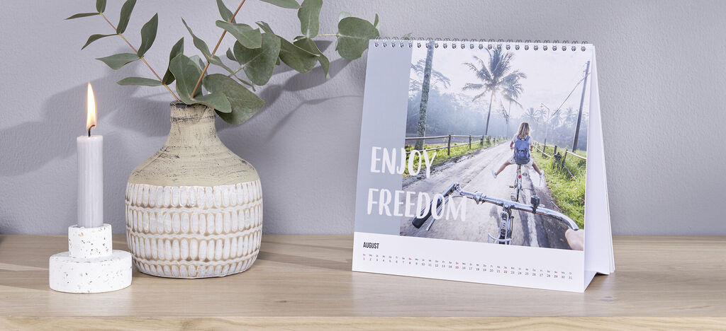 Bureaukalender met fietser op weg tussen palmbomen en tekst enjoy freedom